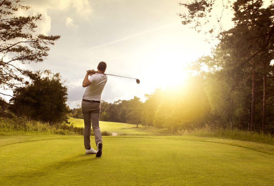 Man playing golf on a golf course in the sun