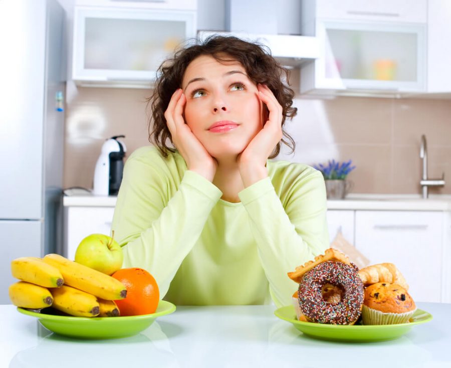 Woman choosing between Fruits and Sweets