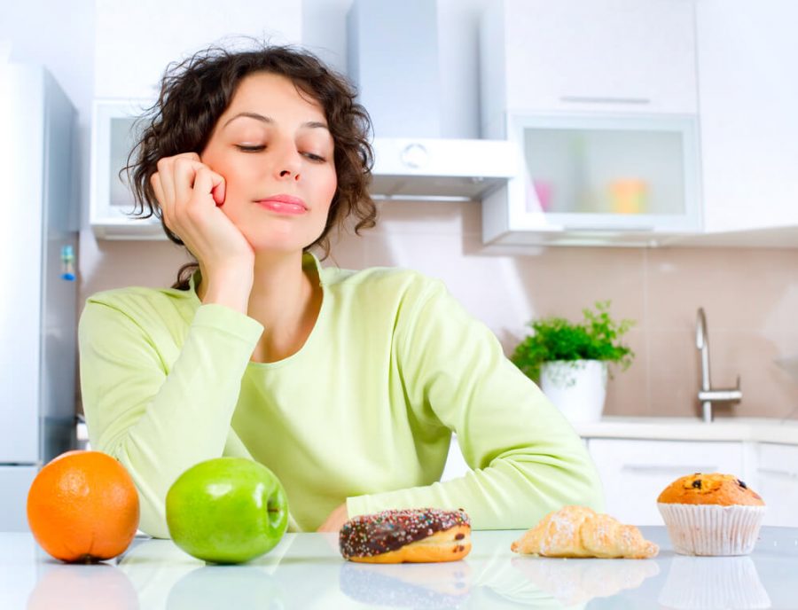 Woman choosing between Fruits and Sweets